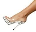 A woman 's foot wearing clear heels with high heels.