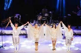 A group of people in white costumes on stage.