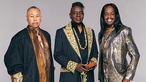 Three men in suits and scarves posing for a picture.