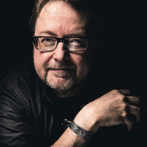 A man with glasses and a beard is posing for the camera.